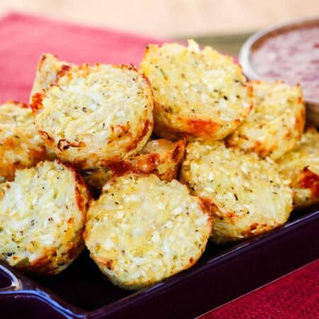 Cauliflower tots piled up on a purple dish.