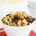 Granola in a white bowl on a red napkin with text overlay that says "Almond Butter Granola".