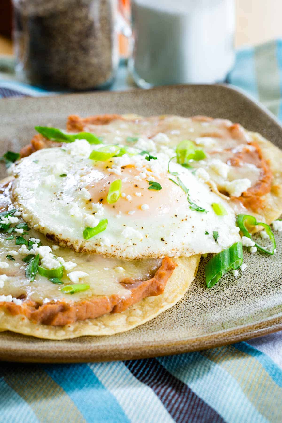 A plate of breakfast tostadas garnished with green onions.