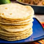 A stack of corn tortillas on a blue plate.