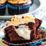 A chocolate cupcake with peanut butter frosting cut in half to show the creamy banana filling.
