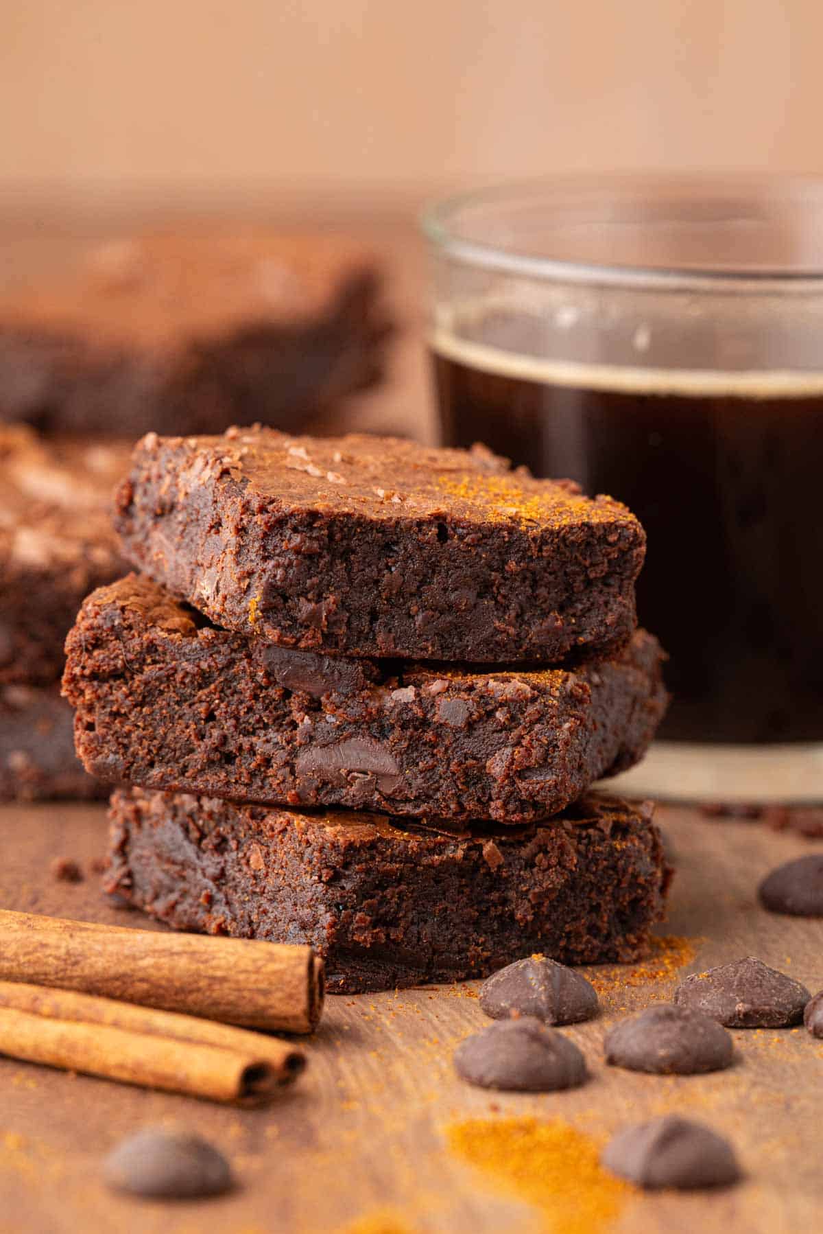 Fudgy, rich, and warmly spiced Mexican brownies are deeply dark and not too sweet. Easily made gluten-free! A stack of Mexican brownies with coffee in the background.