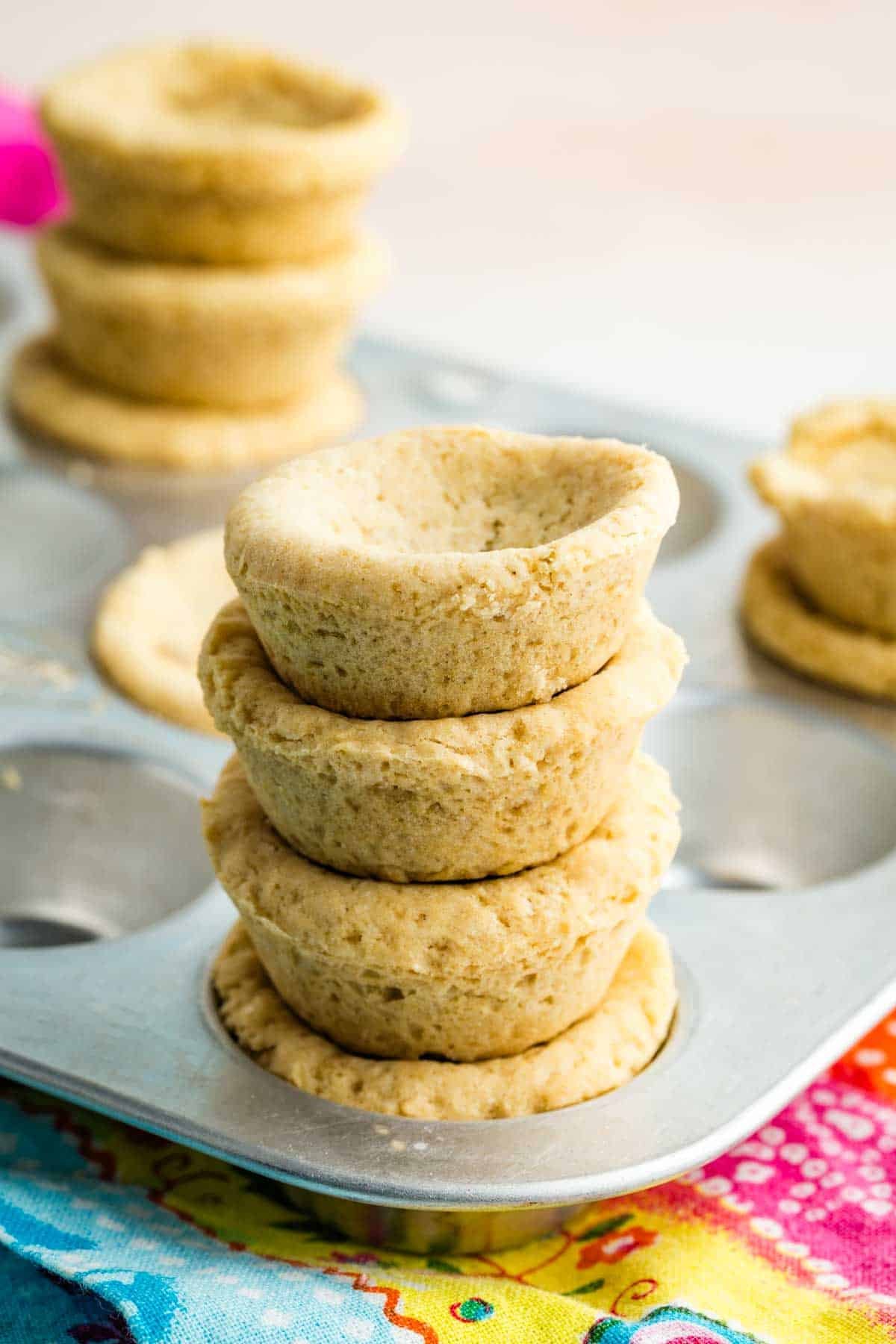 Stacks of baked sugar cookie cups on a baking tin.
