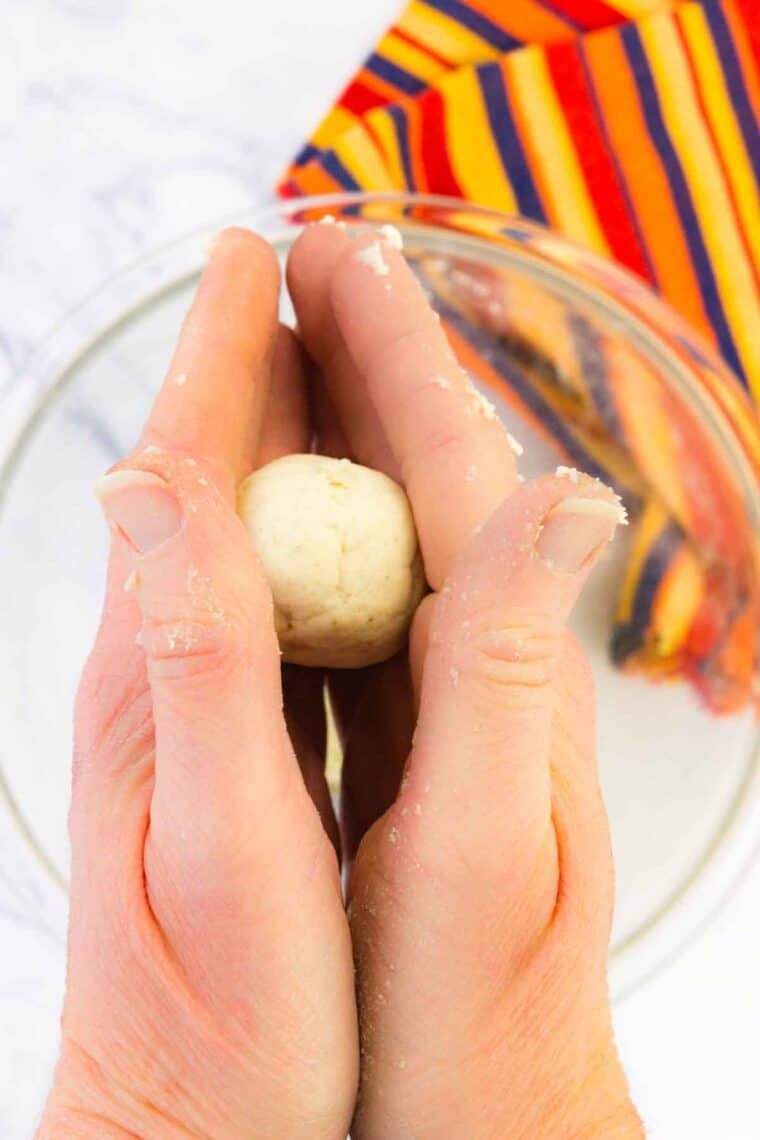 Hands form a ball of tortilla dough.