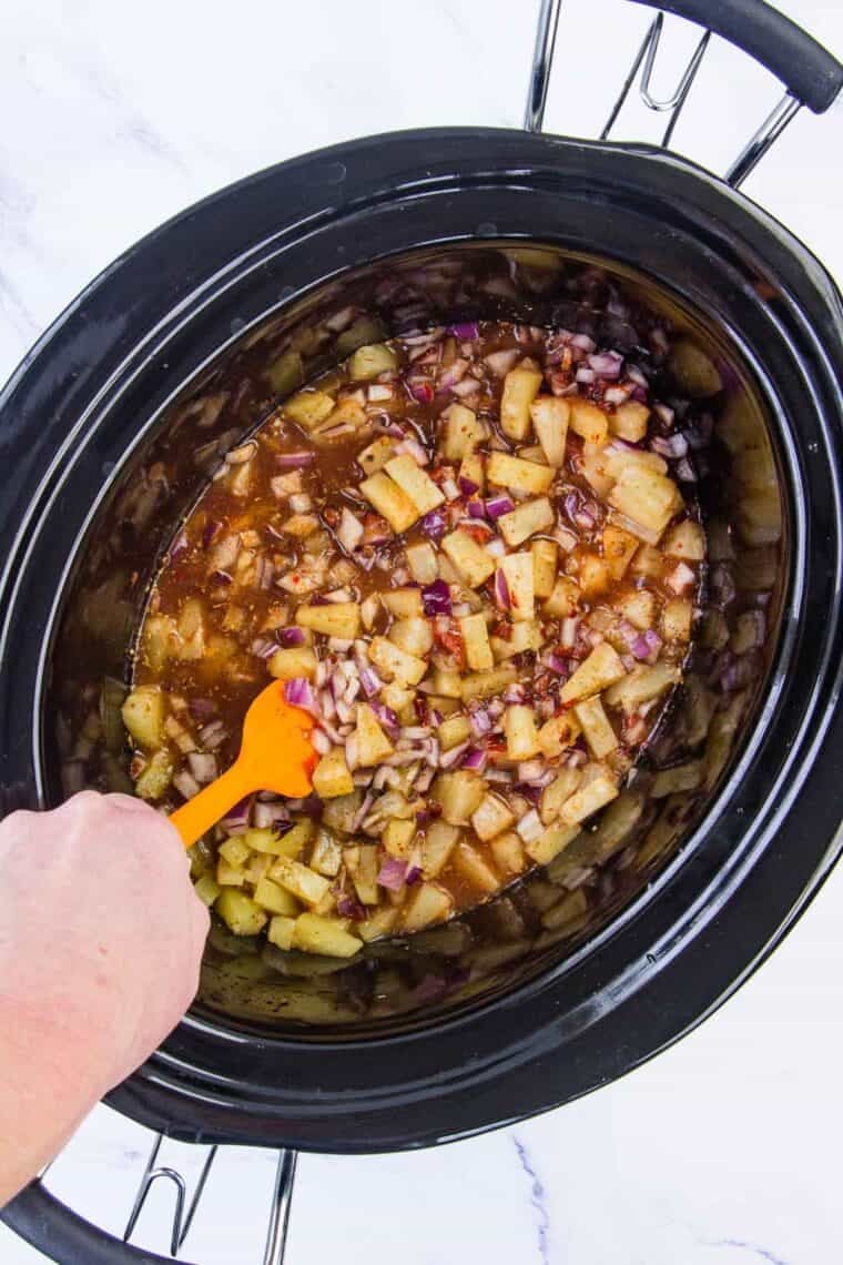 Barbacoa sauce including pineapple is stirred in a crockpot.