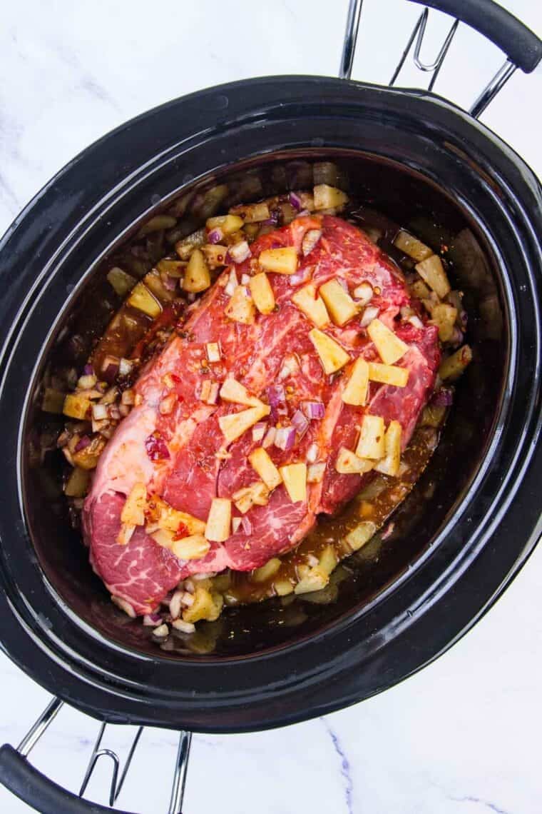 Chuck roast in a crockpot with seasonings to make barbacoa.