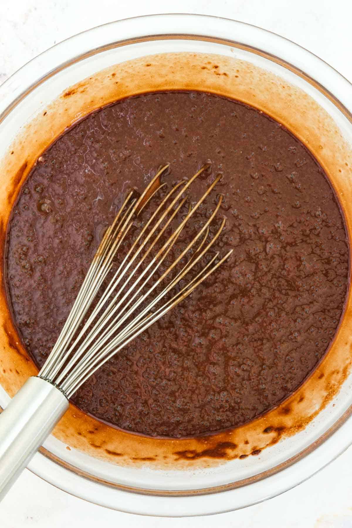 A whisk in a bowl of cupcake batter.