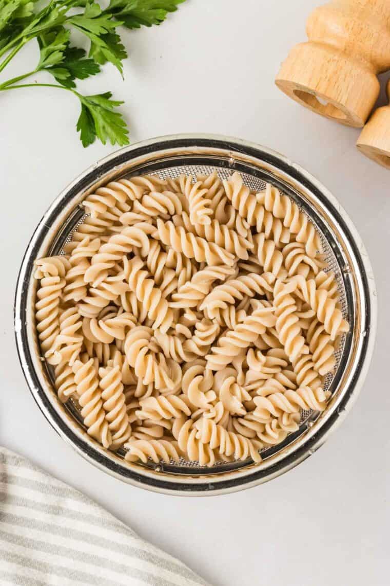Garlic parmesan chicken pasta drapes tender chicken breasts in a rich and creamy sauce that's paired with gluten free pasta. A bowl of cooked gluten-free rotini pasta.