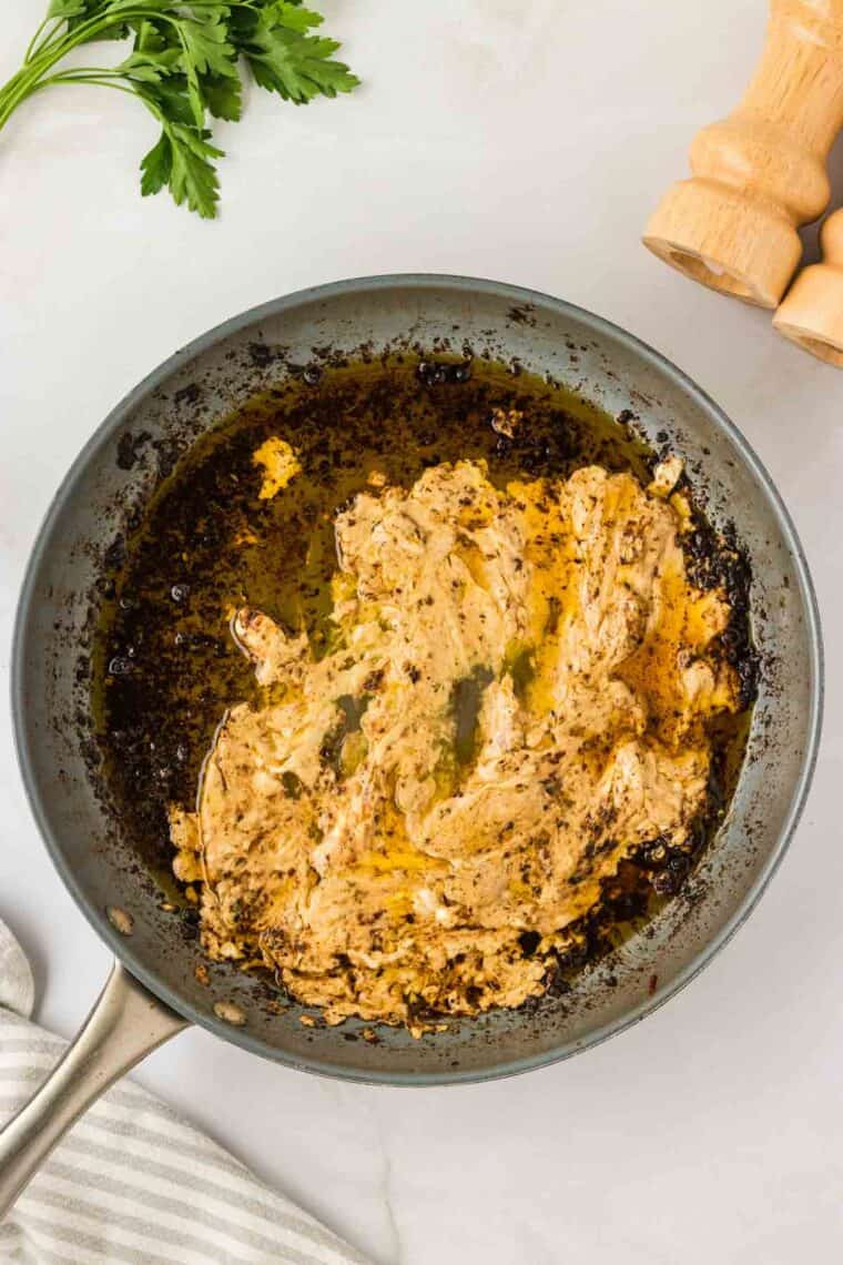 Garlic parmesan chicken pasta drapes tender chicken breasts in a rich and creamy sauce that's paired with gluten free pasta. Cream cheese is mixed into a pan of sauce.