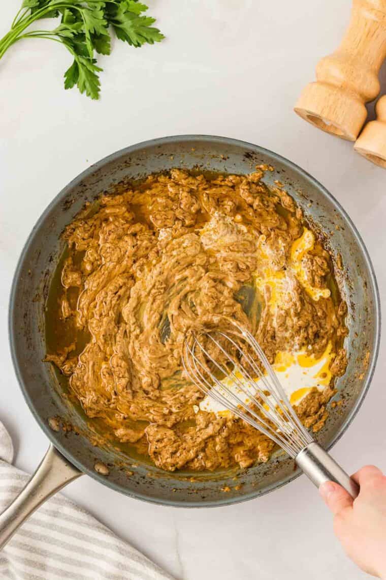 Garlic parmesan chicken pasta drapes tender chicken breasts in a rich and creamy sauce that's paired with gluten free pasta. Cream is whisked into a pan of creamy pasta sauce.