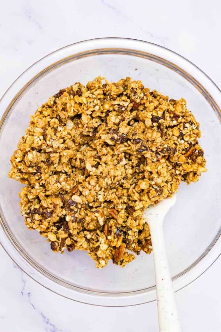 A glass bowl of no bake granola bars stirred with a spoon.