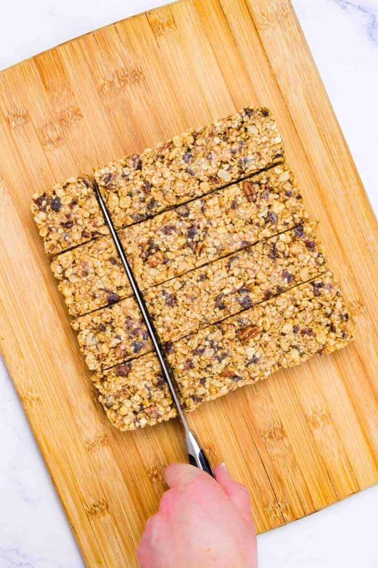 A knife cuts a batch of no bake granola bars into squares.