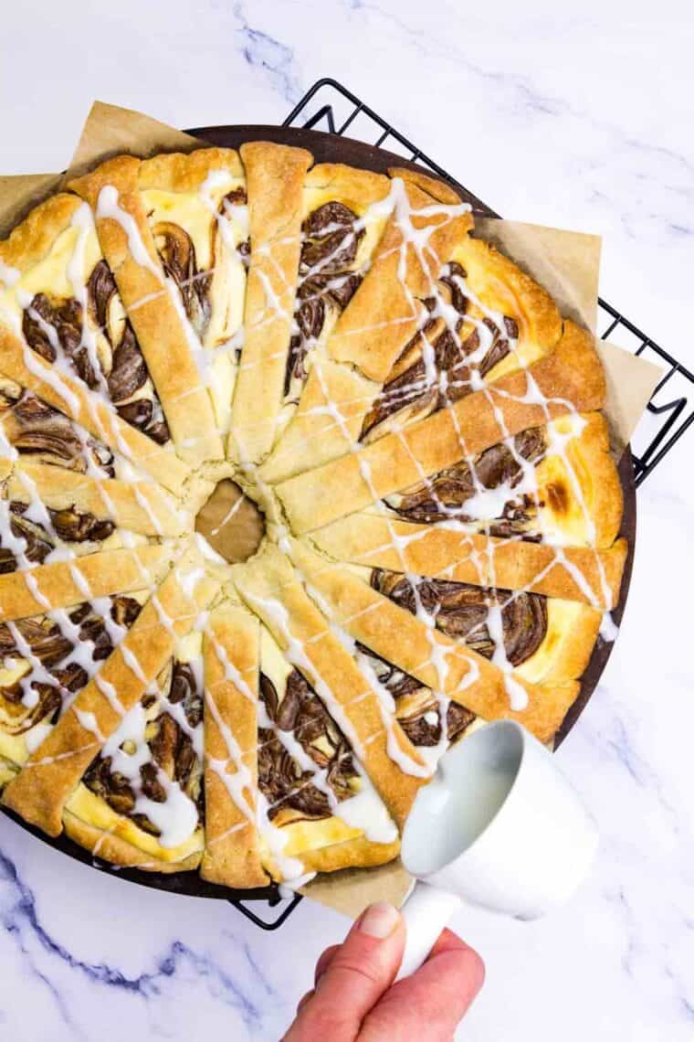 White icing is drizzled over a baked Nutella pastry.