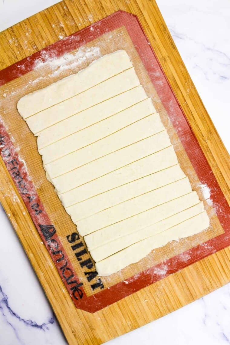 A rectangle of crescent rolls dough is cut into sliced.