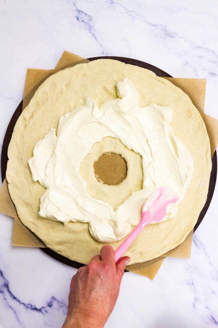 Cream cheese filling is spread onto a round of crescent dough.