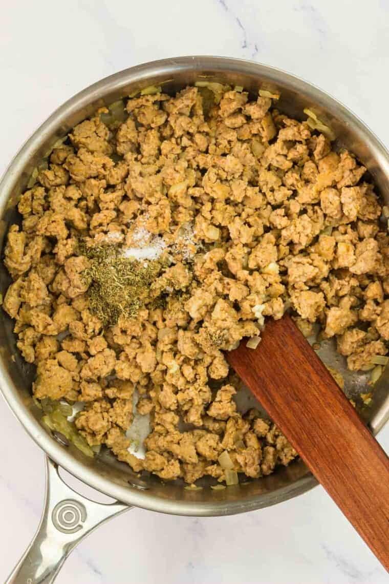 Seasonings added to browning turkey sausage in a pan.