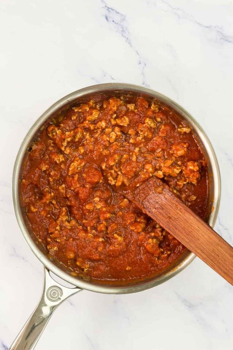 Turkey sausage and tomato sauce stirred in a pan.