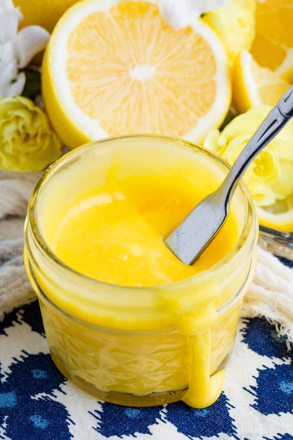 A spoon dips into a jar of lemon curd.