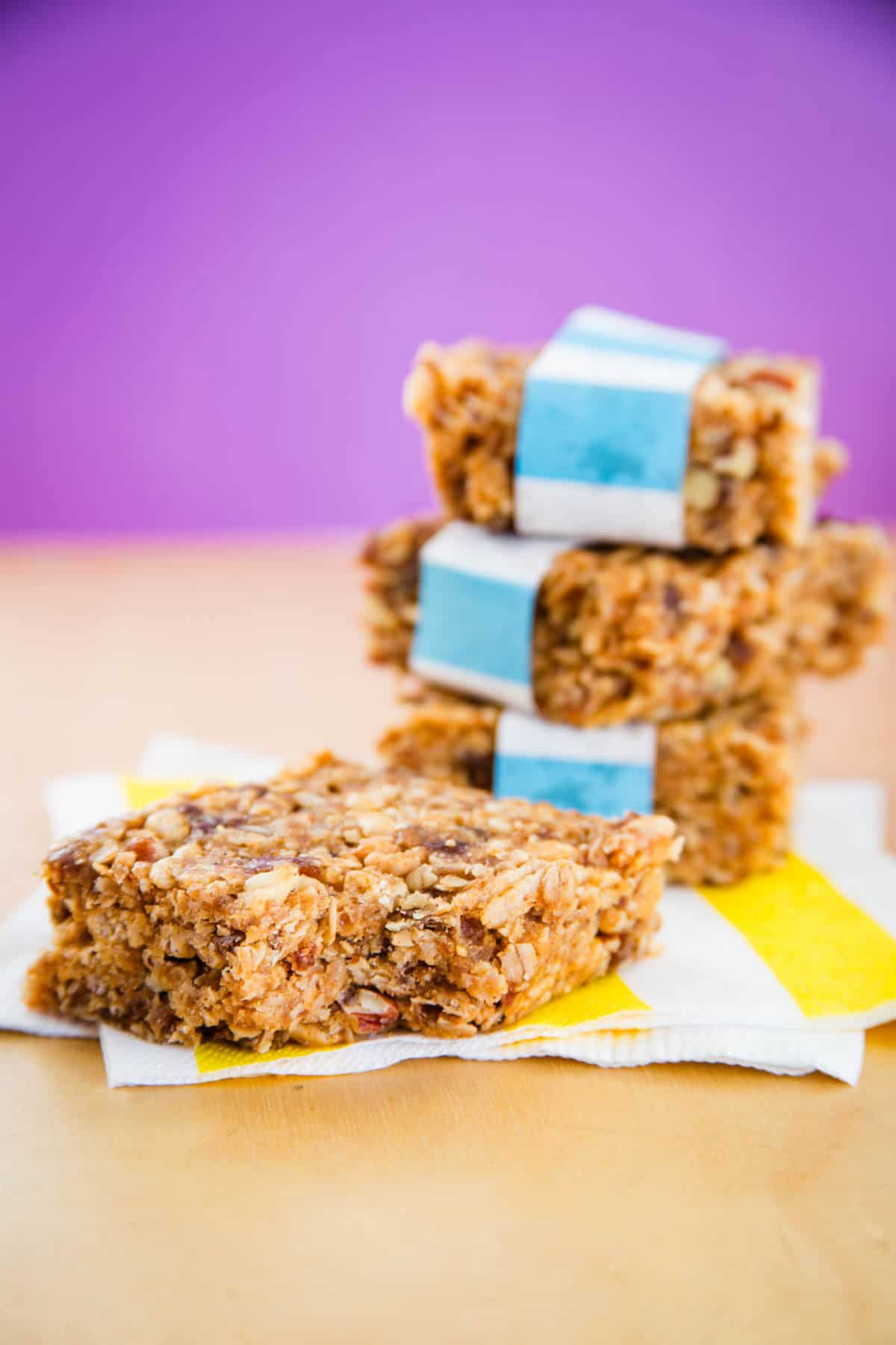 No bake granola bars are naturally sweetened and gluten free, with chewy oats and crunchy walnuts swirled with peanut butter and honey. A stack of three no bake granola bars and a bar next to it.