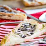 White icing drizzled over a slice of Nutella pastry and a fork on a plate.