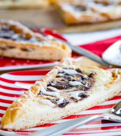 White icing drizzled over a slice of Nutella pastry and a fork on a plate.