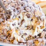 A closeup of the cream cheese interior of a dessert cheese ball coated in Muddy Buddy snack mix.