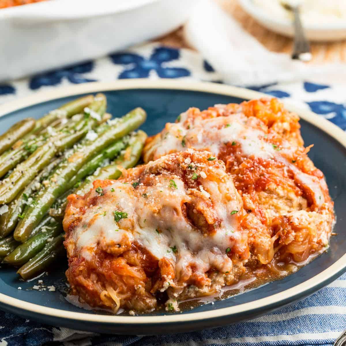 A plate with a portion pf spaghetti squash lasagna and a side of green beans.