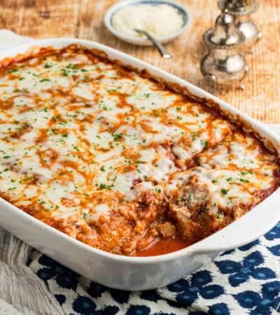 A white baking dish full of spaghetti squash lasagna with one portion removed.