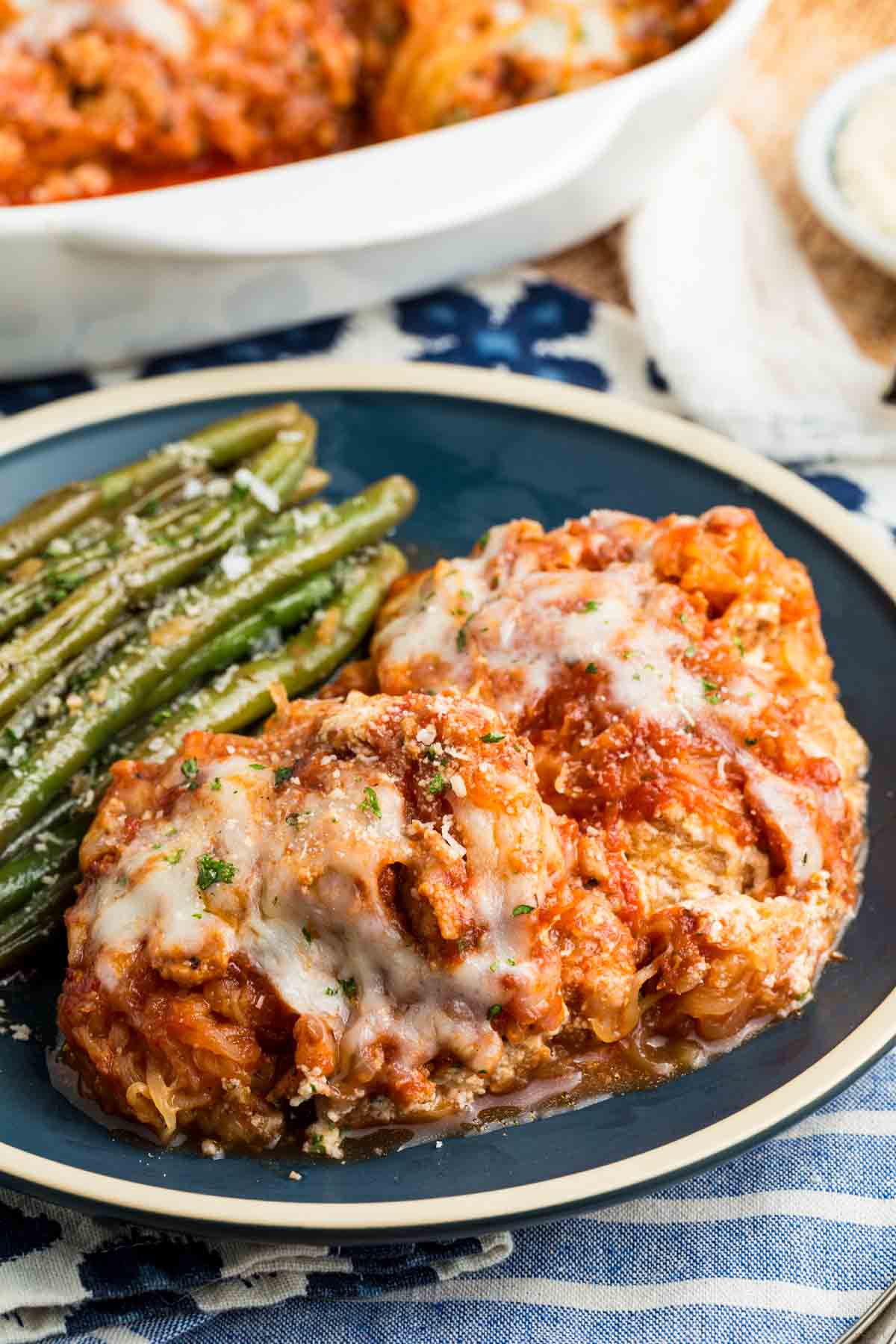 Green beans are served on a plate next to a piece of spaghetti squash lasagna.