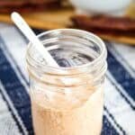 A jar of bbq ranch dressing with a spoon on a napkin.