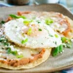 Two tostada shells topped with beans, cheese, and eggs on a plate with text overlay that says "Breakfast Tostadas".