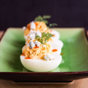 A row of buffalo deviled eggs on a green plate.