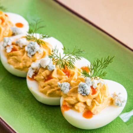 A row of buffalo deviled eggs on a green rectangular plate.