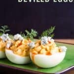 Deviled eggs with hot sauce, blue cheese, and dill on a green plate with text overlay that says "Buffalo Deviled Eggs".