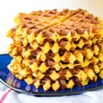 A blue plate holds a stack of cheesy polenta waffles.