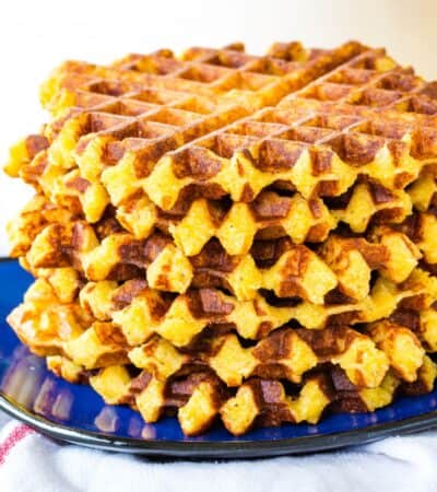 A blue plate holds a stack of cheesy polenta waffles.