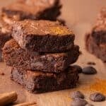Three stacked brownies surrounded by cinnamon sticks and chocolate chips with text overlay that says "Gluten Free Mexican Chocolate Brownies".