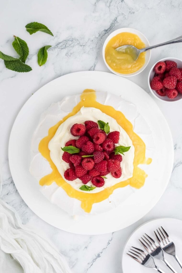 Raspberries and fresh mint added to a top of a pavlova.
