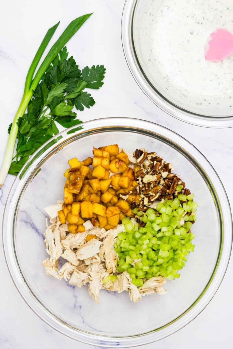 The ingredients for pecan chicken salad, minus the dressing, are added to a bowl.