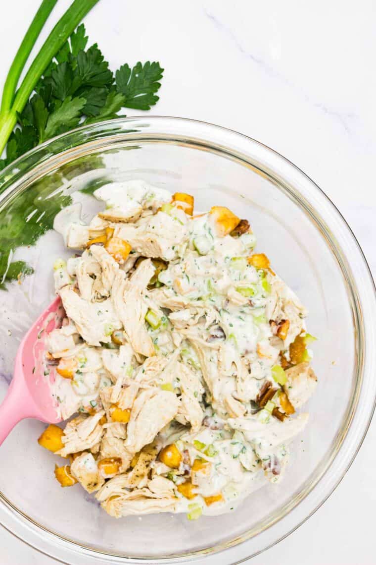 Dressing is mixed into pecan chicke salad.