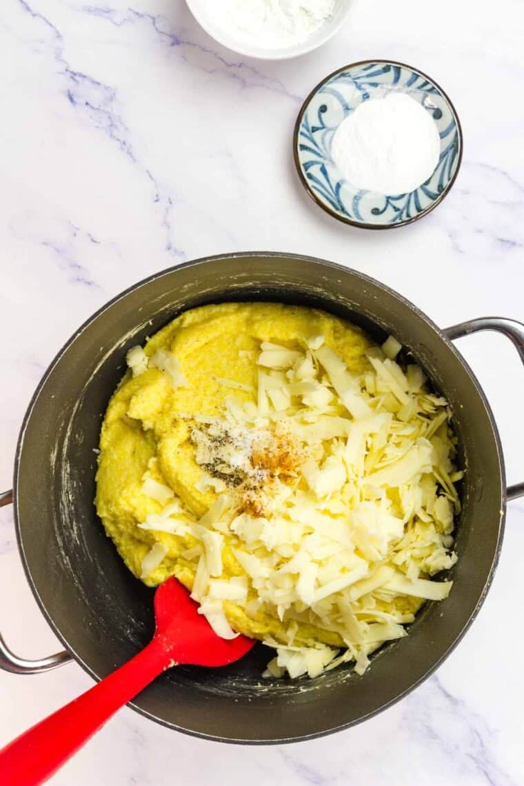 Spices and cheese are added to cooked cornmeal.