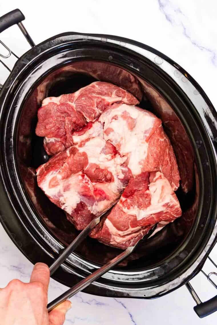 Seasoned pork is added to a slow cooker.