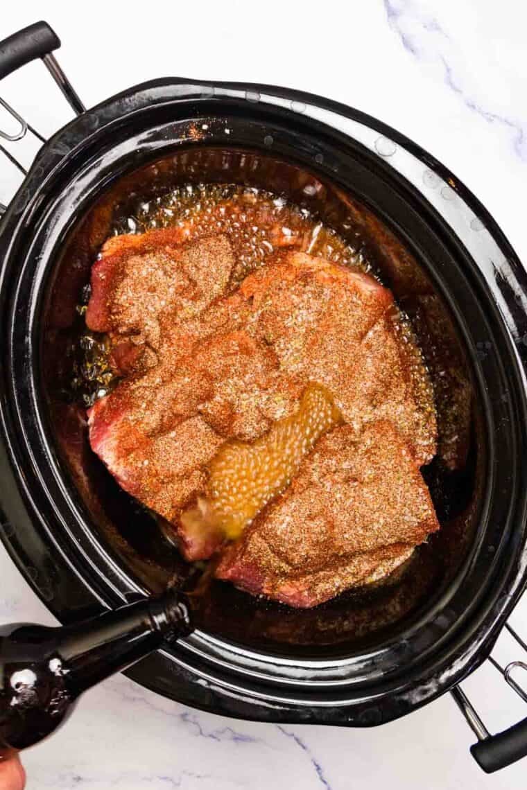 Liquid is added to pork in a slow cooker.