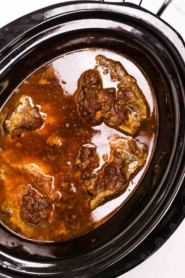 Spices and root beer are added to pork in a slow cooker.