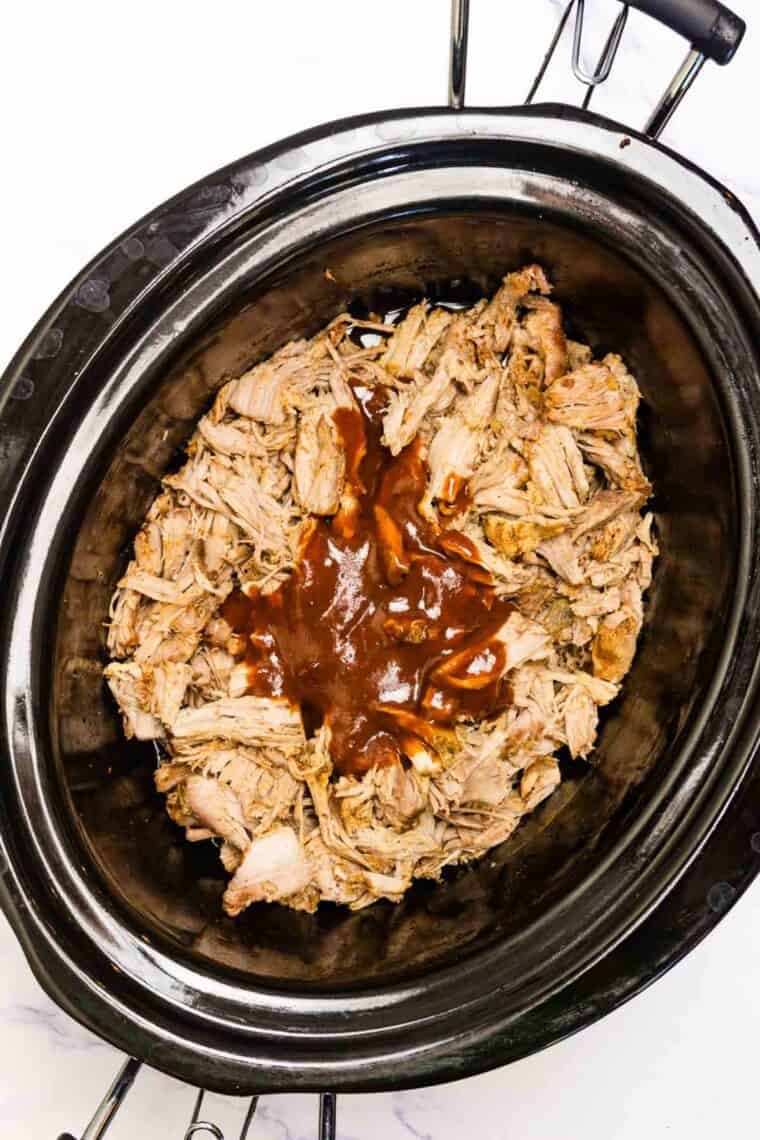 The shredded pork is added back to the slow cooker.