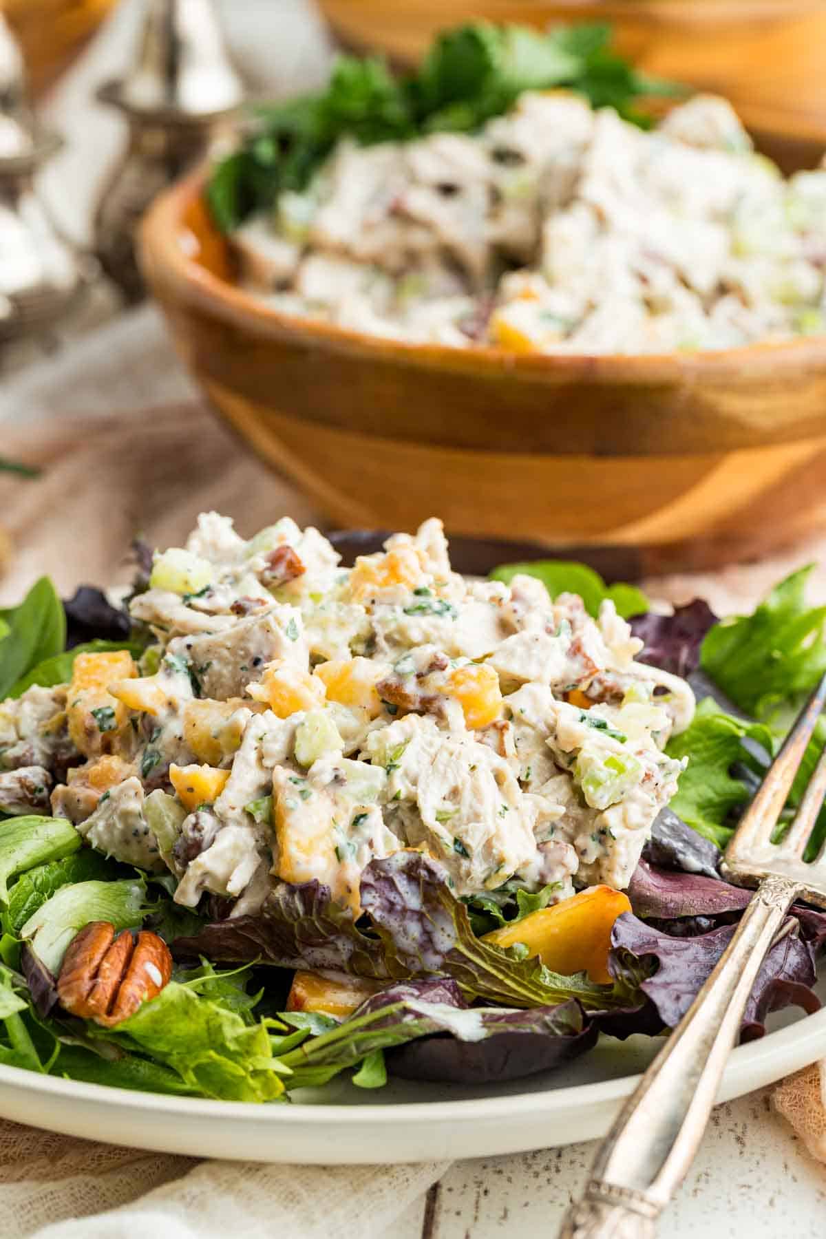A scoop of pecan chicken salad is served on salad green.