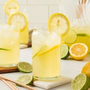 Glasses of lemon limeade with straws and sliced citrus.