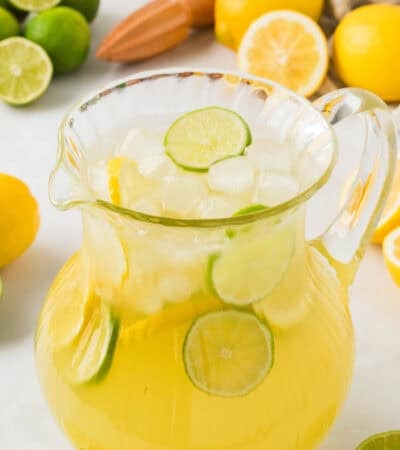 A glass pitcher full of lemon limeade and lemon and lime slices.