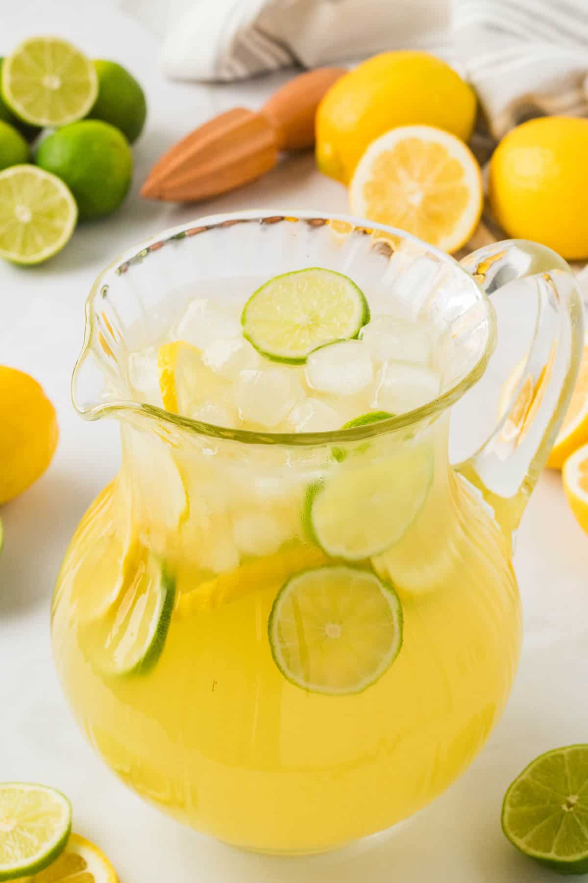 Lemon limeade is a refreshing blend of tart and sweet lemon and lime juices naturally sweetened with agave nectar. A glass pitcher full of lemon limeade and lemon and lime slices.