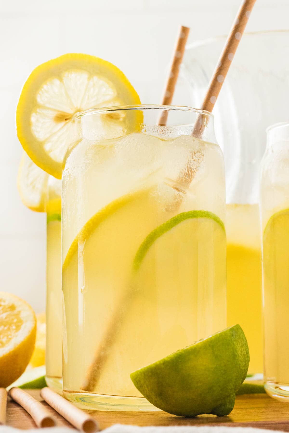 Glasses of lemon limeade with straws and sliced citrus.
